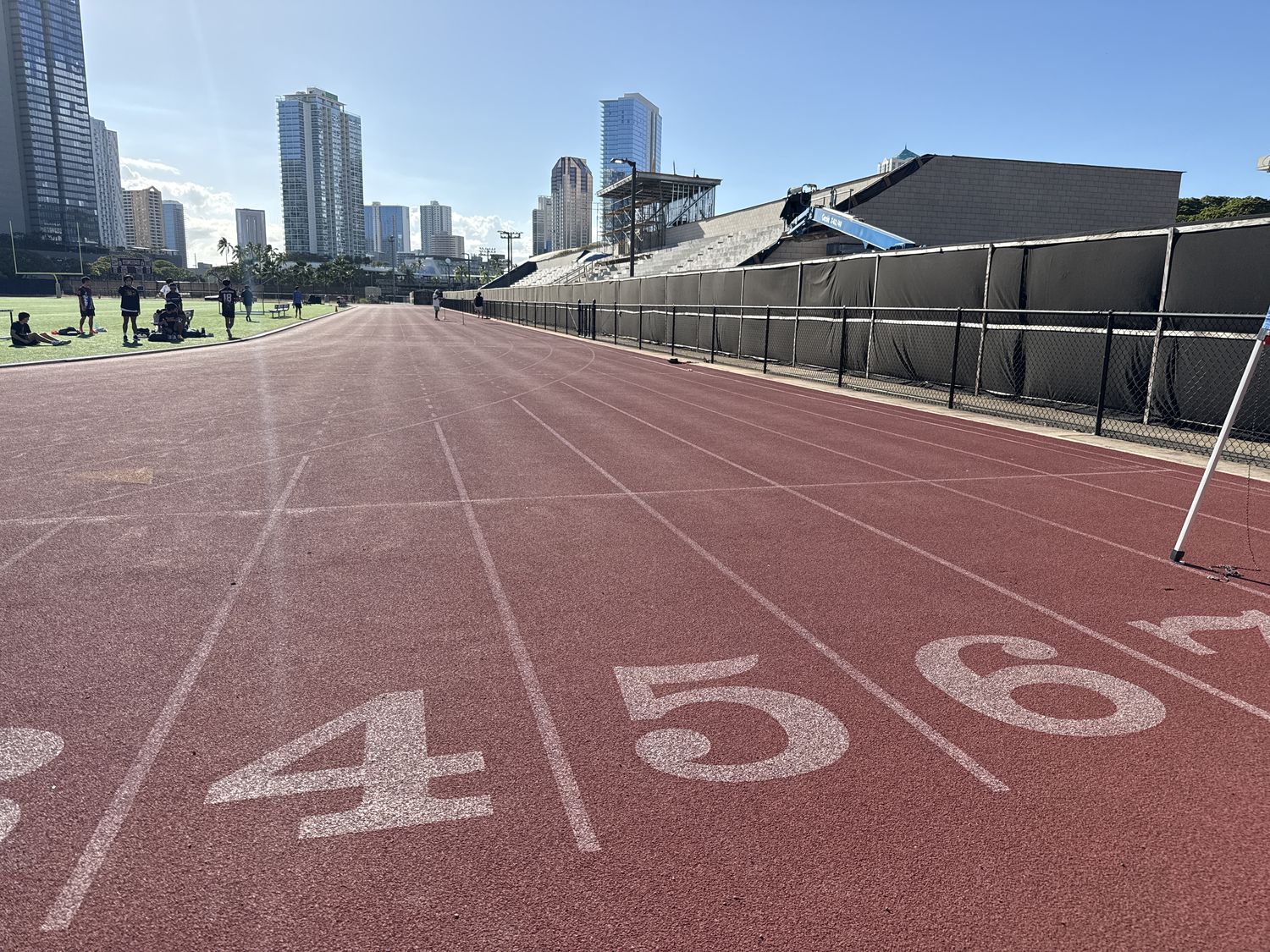 Lane numbers on a red track with bleachers and skyline