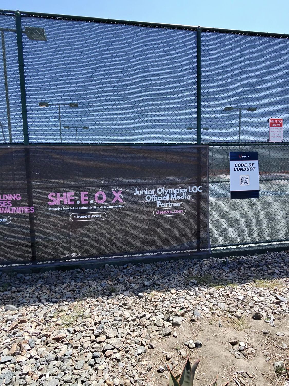 Sponsor banners and media partner signage on the venue fence at the USATF Junior Olympics