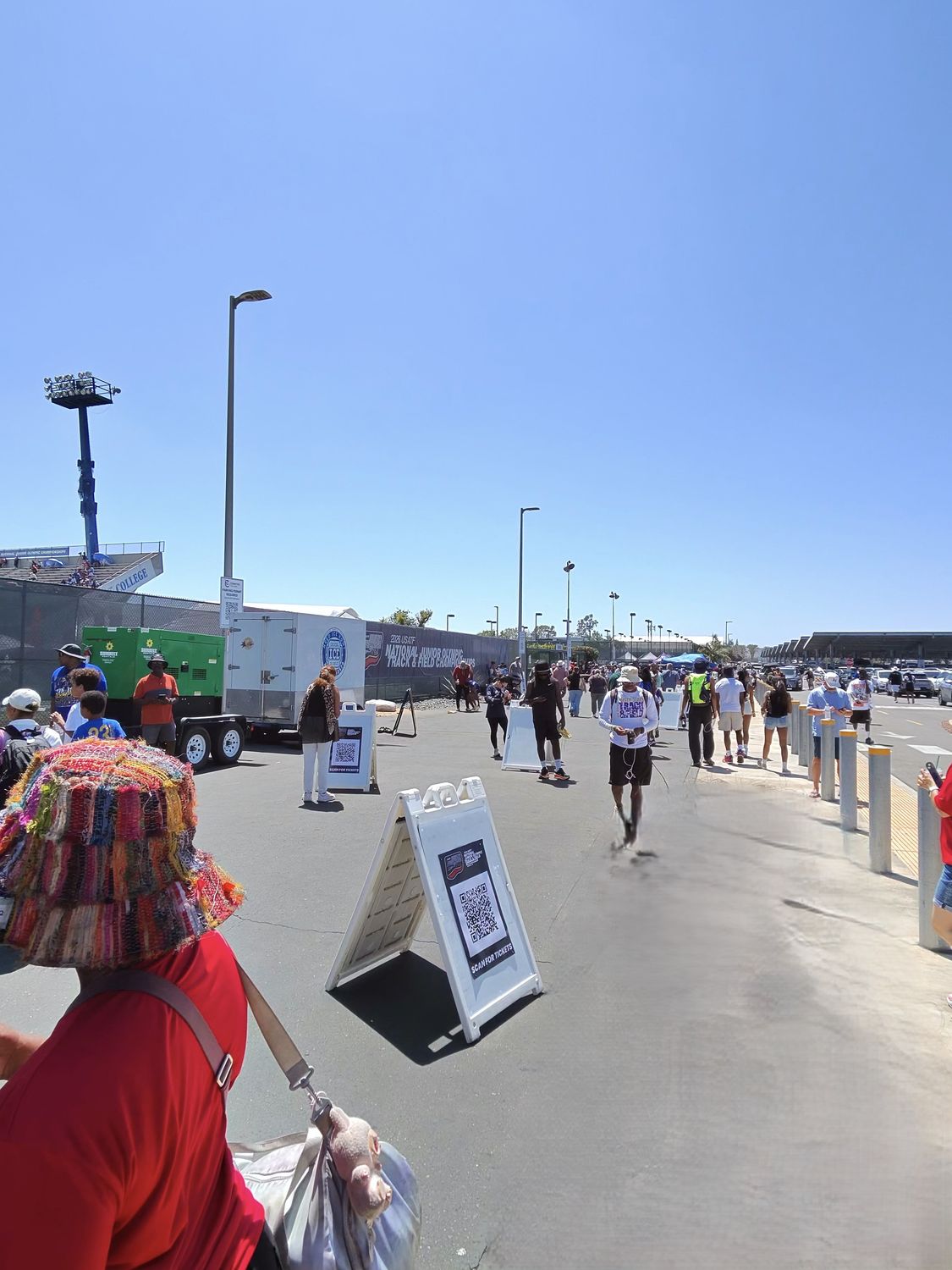Spectators and athletes walking near the entrance and staging areas at the Junior Olympics