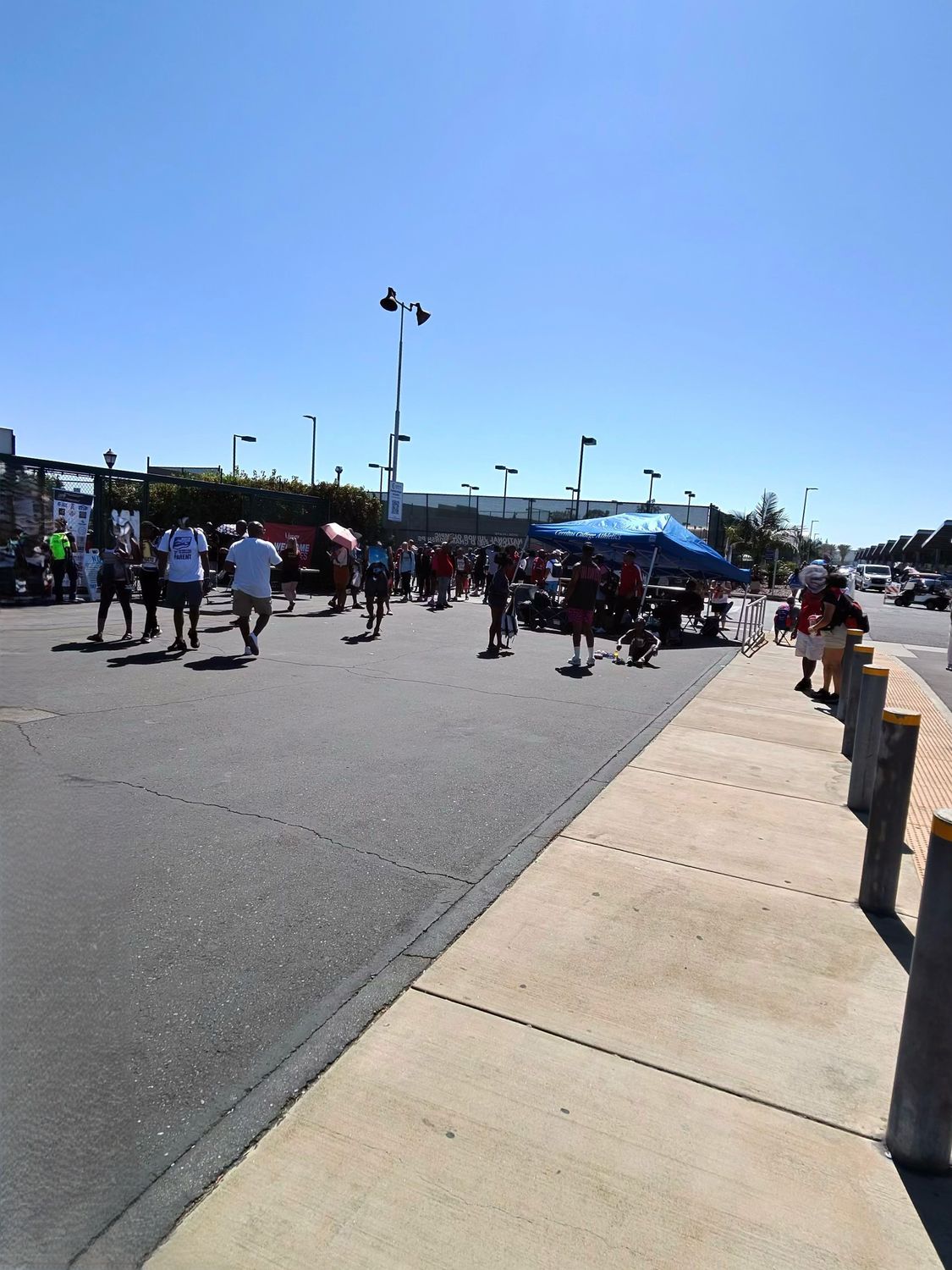 Crowds of spectators and athletes moving through the venue area outside the stadium