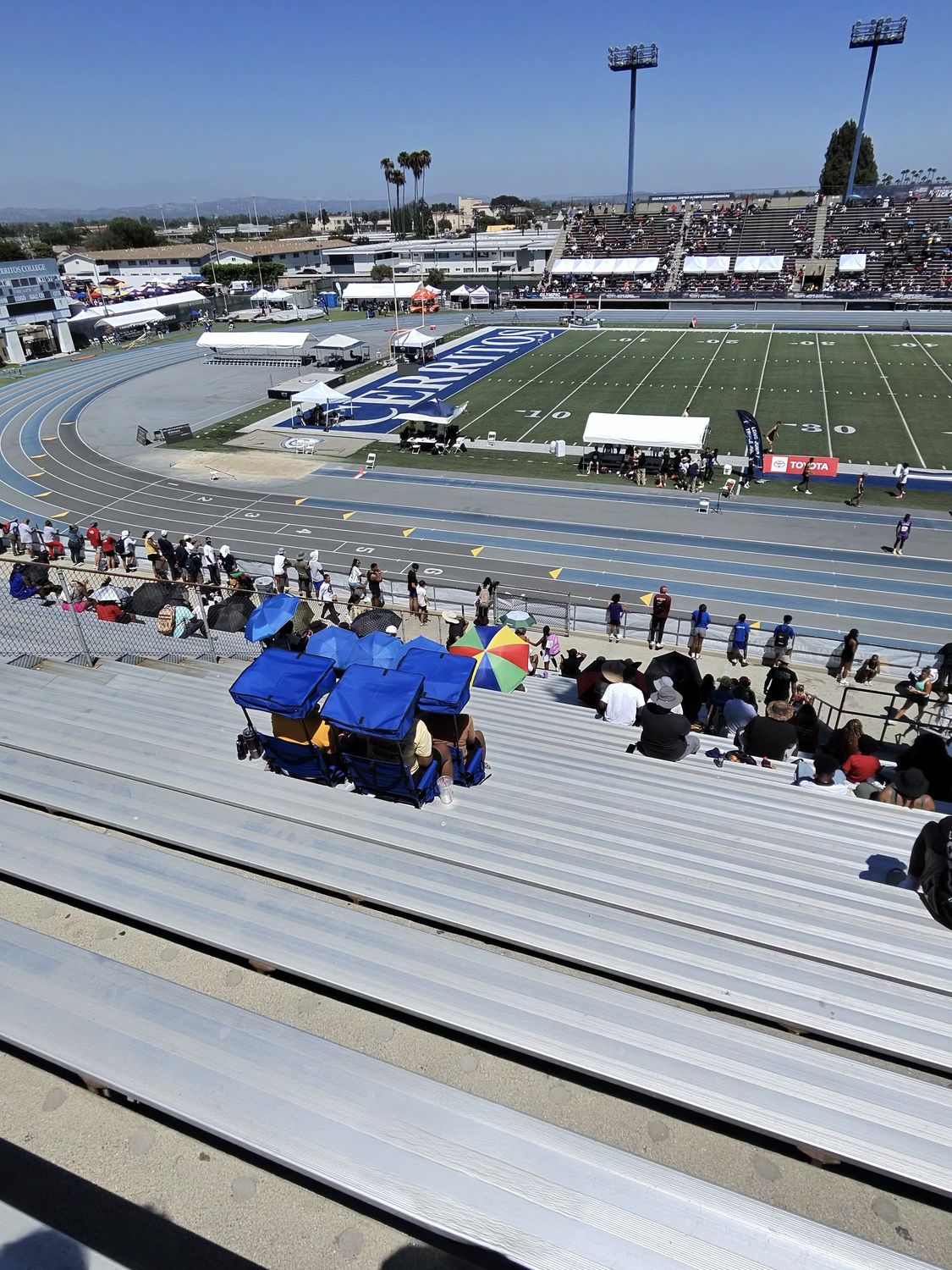 Spectators with shade canopies in the bleachers at a USATF meet