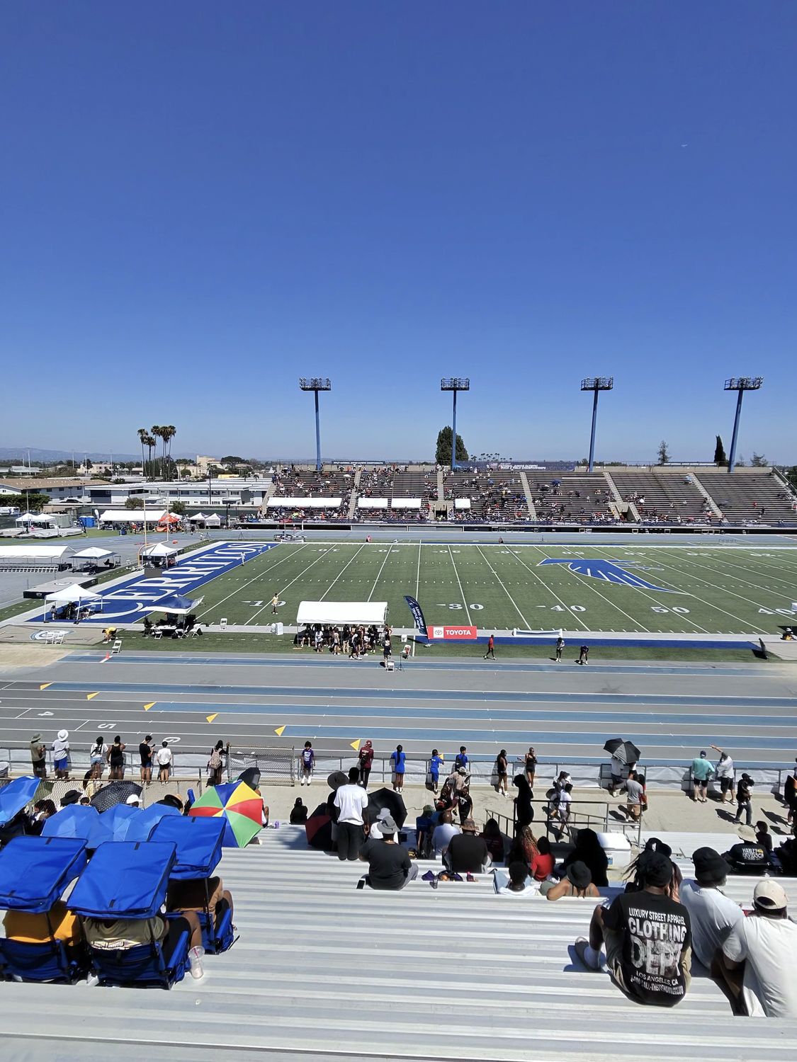 View from the top of the bleachers during a race with stadium seats, canopies, and umbrellas visible