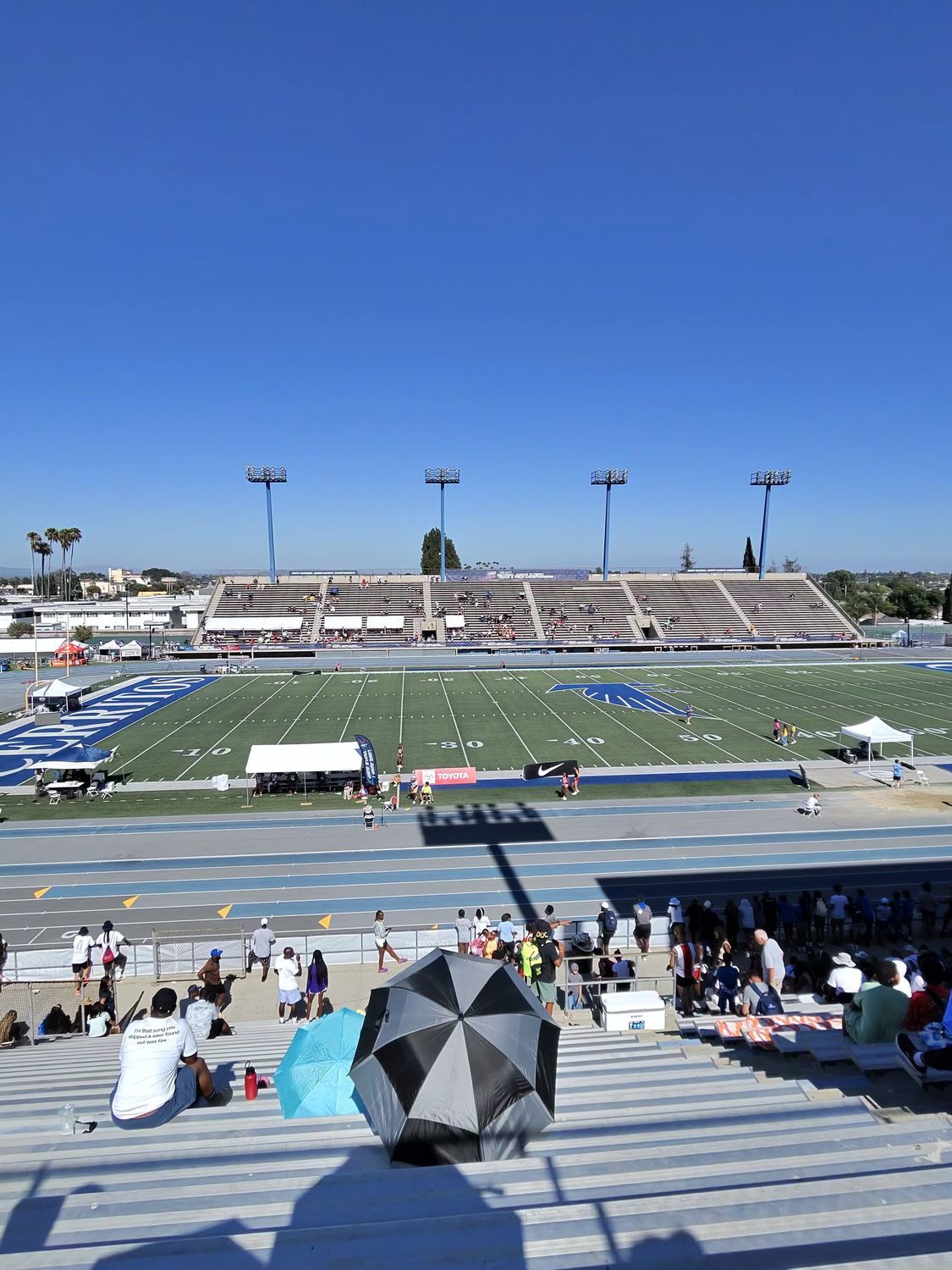 UV resistant umbrella providing shade in the bleachers at Cerritos College with the stadium and parking lot visible