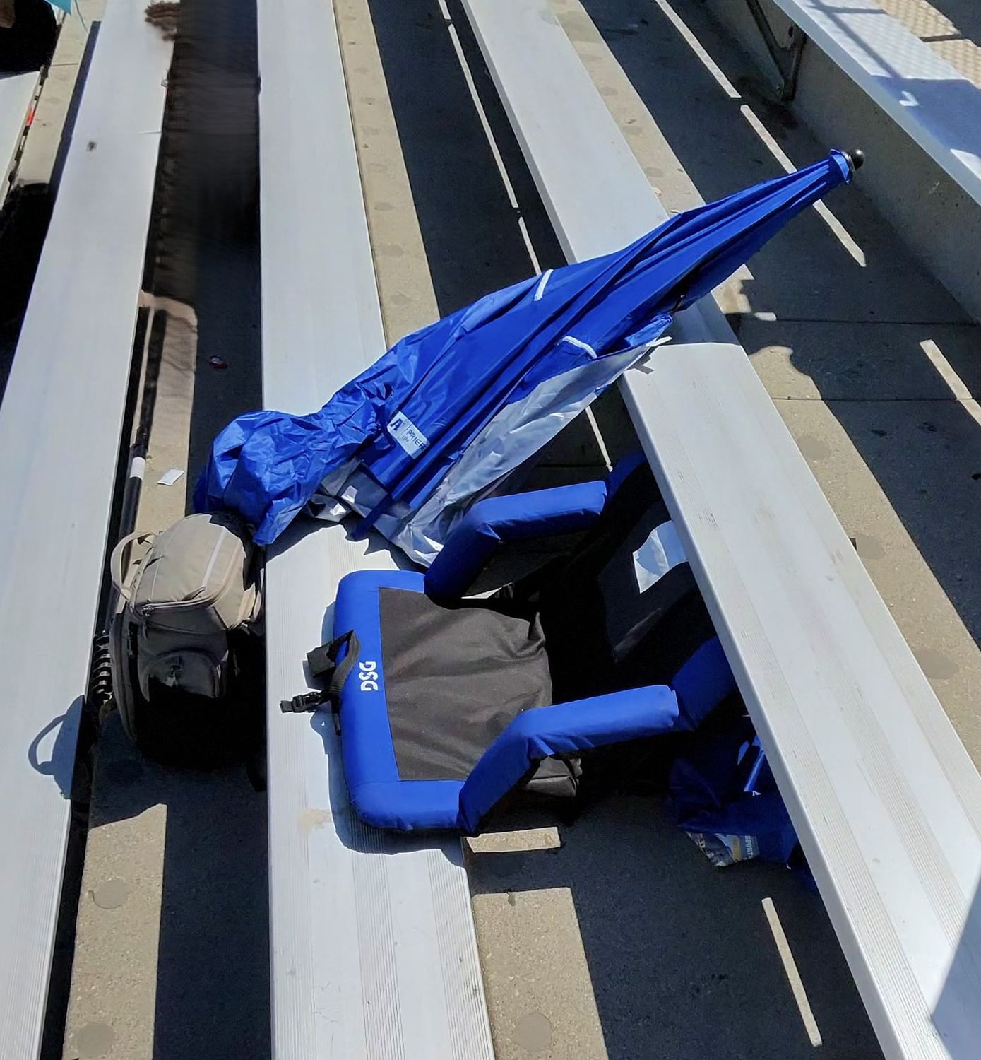A bleacher setup showing UV umbrella, cushion seat, and cooler - the essentials for a track meet